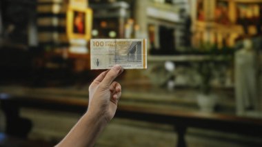 Şehir caddesinde Danimarka kronu banknotları tutan adam, şehir yaşamını ve döviz alışverişini sergiliyor. Finansal işlem unsurlarına odaklanıyor..