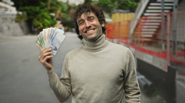 Güney Kore 'de gülümseyen ve elinde tutan İspanyol bir adam açık havada bir şehir caddesinde para kazandı, canlı bir şehir ortamında mutluluk ve başarı yaydı..