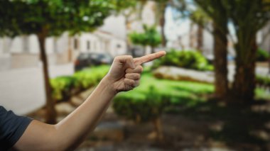 Man pointing hand in an outdoor city street with blurred urban background, highlighting a focus on human gesture and interaction in public environment. clipart