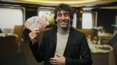 İçerde elinde Tayland banknotları tutarak gülümseyen bir adam zarif bir geçmişi olan bir restoranda rahat bir ortamda neşe ve başarı anı yakalıyor..