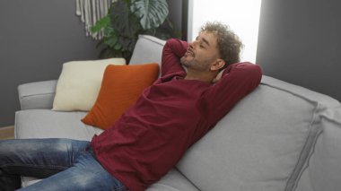 Genç İspanyol bir adam modern bir apartman dairesinde rahat bir koltukta dinleniyor. Huzur ve rahatlama hissi yayıyor..