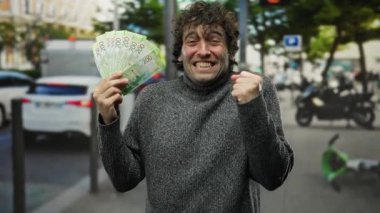 İspanyol adam kalabalık bir şehir caddesinde neşeli bir şekilde Rus rublesini tutuyor. İfadesinde ve vücut dilinde belirginlik var. Bulanık şehir aktiviteleriyle çevrili..