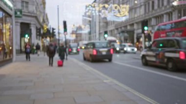 Londra caddesinde kışın bulanık insanlar, ikonik kırmızı otobüs ve bayram süslemeleri klasik bir tatil atmosferi yaratıyor..