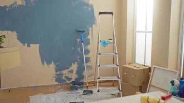 İspanyol bir adam yeni bir evin içini merdiven ve taşınan kutularla boyuyor. Diy dekorasyon ve modern bir apartman dairesinde ev dekorasyonu sergiliyor..