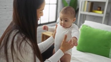 Anne bebeğini sıcak bir yatak odasında sevgi dolu bir şekilde kucağına alıyor sıcak bir evin içinde samimi aile anları sergiliyor..