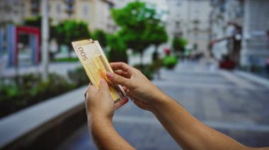 Kentsel bir sokak ortamında Norveç kronlarını sayan bir adam, açık havada finansal yatırım temaları vurguluyor.