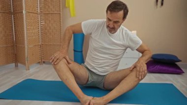 Huzurlu spa ortamında yoga yapan ve arka planda hasır perde olan bir adam..
