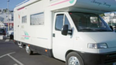 Bulanık şehir unsurları ve bokeh etkisi içeren arka planda park halindeki karavan seyahat ve eğlence öneriyor.