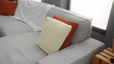 Genç adam rahat bir kanepede rahat bir şekilde rahat bir oturma odasında rahat bir dekor ve hareketli yastıklarla rahat bir ortam yaratıyor..