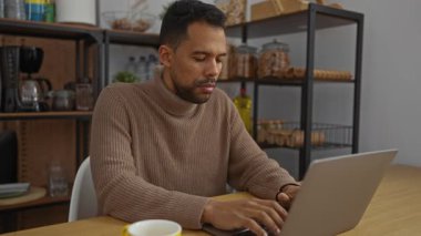 Ofiste dizüstü bilgisayarda çalışan İspanyol bir adam molada, kapalı bir çalışma alanındaki kavanozlar ve bardaklarla dolu raflarla esneme hareketleri yapıyor..