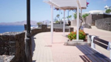 Lanzarote İspanya sahnesi, arka planda okyanus manzarasında gezinen bokeh bankları ve çiçeklerle çözünmüş bir yol gösteriyor.