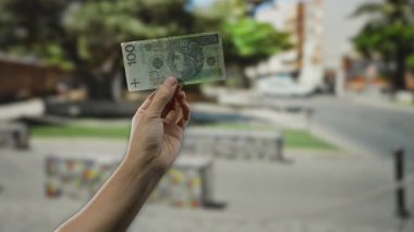Şehir sokaklarında elinde Polonya banknotları tutan bir adam, şehir ortamında para ve ekonomik temaları vurguluyor.