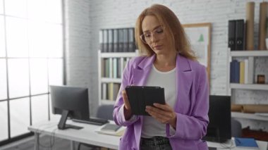 Modern ofis ortamında, parlak ışık ve profesyonel atmosfere sahip tablet kullanan kadın, teknoloji ve iş ortamını aktarıyor.