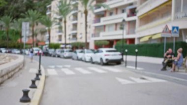 Bulanık sokak manzarası Palmiye çizgili yol, odak dışı binalar, park edilmiş arabalar ve dışarıda oturan insanlar.