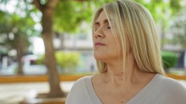 Şehir merkezindeki ağaçlarla çevrili şehir parkında sakin bir anın tadını çıkaran bir kadın. Yumuşak doğal ışıkla rahatlık ve sükunet yayıyor..