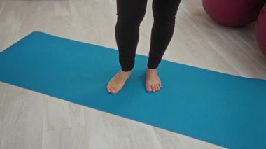 Spor salonunda çıplak ayakla yoga yapan hamile bir kadın spor salonunda spor topları ve yastıklarla çıplak ayakla..