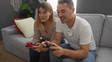 Oturma odasında oyun oynayan bir çift, oyun kontrolörleriyle birlikte kanepede oturup eğlenen kadın ve erkeklerle eğleniyor..