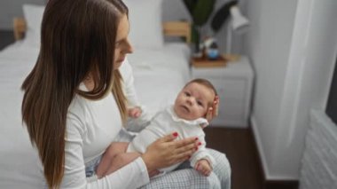 Anne, küçük kızını sıcak bir yatak odasında sevgi dolu bir şekilde kucaklıyor. Sıcak bir evde şefkatli aile anları sergiliyor..