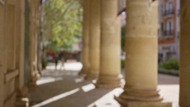 Ön planda çözünmüş kolonlar ve arka planda yürüyen insanlar ile bulanık bir açık hava sahnesi