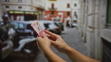 Meşgul bir şehir caddesinde Meksika pezosu tutan eller, canlı bir şehir ortamında iş ve yatırım kavramını yakalıyor..