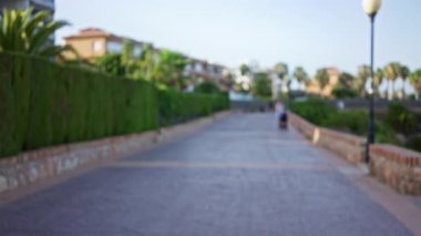 Açık hava yolu bulanık yeşillik bulanık sokak, bulanık lamba direği, ve açık bir gökyüzüne karşı evlerin uzak bataklığı