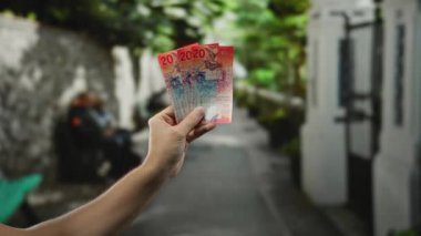 Şehrin arka planında bulanık bir sokakta el ele tutuşan İsviçre banknotları, açık şehir ortamında para birimi vurgulanıyor, finans kavramını erkek bakış açısıyla betimliyor.