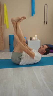 Paspaslar, mumlar ve hareketli dekorlarla çevrili bir huzur stüdyosunda yoga yapan bir adam rahatlama ve zindelik öneriyor..