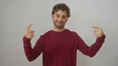 İspanyol asıllı genç adam kendine güvenen, tişört giyen, kendini izole edilmiş beyaz arka planda gösteren, mutlu ve kendinden emin görünen.