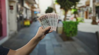 Bangladeş banknotları elinde tutan bir adam, şehir yaşamının ortasında finans ve para birimini gösteren bir açık şehir caddesinde.