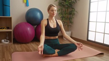 Egzersiz topları ve bitkilerle yoga minderi üzerinde meditasyon yapan bir kadın spor meraklıları ve farkındalık uygulayıcıları için iç mekan dekoru sergiliyor..