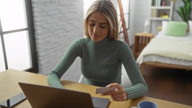 Diz üstü bilgisayar kullanan ve açık pencereli ve rahat dekorlu rahat yatak odası ayarlarında tutan kadın, online alışverişi veya evden çalışmayı öneriyor.