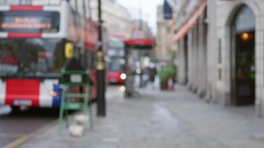 Londra caddesinde çift katlı otobüsler, kaldırımda yürüyen bir adam ve İngiltere 'de sonbaharda kış atmosferini gösteren kentsel binalar..