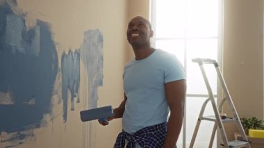 Genç adam, modern ev oturma odasının yakınındaki merdivenle duvarları maviye boyuyor. İç dekorasyonu çok keyifli..