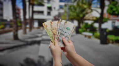 Perulu tabanları olan bir kadın şehir sokaklarında iş ve para birimi temalarını resmediyor..