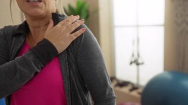 Spor salonunda omuz ağrısı çeken bir kadın spor kıyafetleri giyer, spor kıyafetleri giyer..