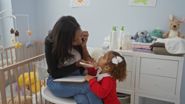 Anne ve kızı, sıcak bir yatak odasında oyuncaklarla çevrili bir beşikle sevgi ve sıcaklık dolu bir aile ortamını paylaşıyorlar..