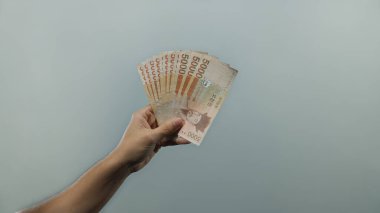 Güney Kore 'yi elinde tutan adam, izole edilmiş beyaz bir arkaplan karşısında, parasal zenginlik ve para birimini minimalist bir ortamda göstererek banknotlar kazandı..
