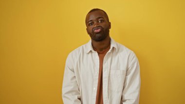 Genç, yakışıklı, afro-amerikalı adam canlı sarı bir arka plana karşı poz verdi, kendine güveni ve tarzı vardı.