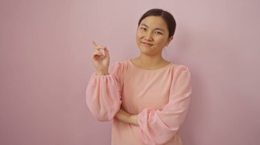 İnzivaya çekilmiş pembe arka planda, açık pembe bluz giyen, zarif ve alımlı bir şekilde gülümseyen kadın..