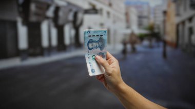 Bir şehir caddesinde Çin Yuan banknotunu elinde tutan adam, kentsel çevredeki para alışverişini veya para alışverişini resmediyor..