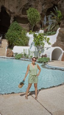 Lagomar, Lanzarote 'da havuz kenarında poz veren genç bir kadın. Arka planda tropik bitkiler ve kaya oluşumları olan kanarya adaları.