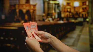 Kilisenin içinde para ve bağış odaklı Malezya halkaları tutan eller iç ruhsal bir ortamda, finansal işlemleri vurguluyor..