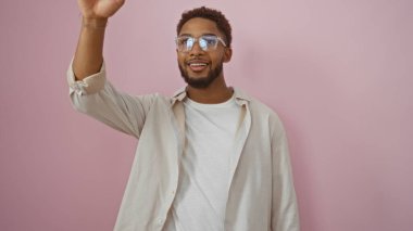 Yakışıklı, gözlüklü, pembe bir arka planda gülümseyen çekici ve dost canlısı bir genç.