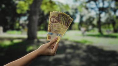 Bir park ortamında el ele tutuşan Macar banknotları bulanık bir bahçe geçmişine karşı para ve finansal kavramlara işaret eden banknotlar sergiliyor..