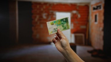 El ele tutuşan İsrail şekeli, iç inşaat sektöründeki kentsel yatırım fırsatlarını gözler önüne sererek tadilat yapılan bir evde.