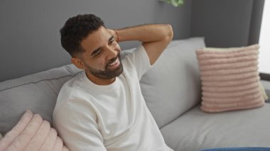 Rahat bir oturma odasında rahat minderleri olan yakışıklı genç bir adam.