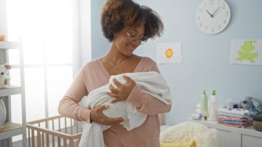 Sıcak yatak odasında, sıcak aile atmosferini gözler önüne seren sıcak yatak odasındaki bebeğe sevgiyle gülümseyen bir kadın..