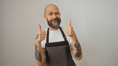 Yakışıklı bir İspanyol, neşeli bir portrede beyaz bir arkaplan karşısında baş parmak işareti yaparken göz kırpıyor.