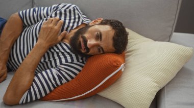 Evdeki kanepede dinlenen sakallı yakışıklı, düşünceli adam.