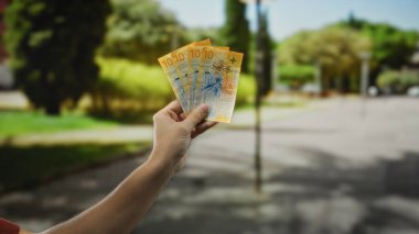 Güneşli bir şehir caddesinde İsviçre frangı banknotları tutan adam, açık şehir ortamında para gösteriyor, bulanık doğal bir geçmişi var..